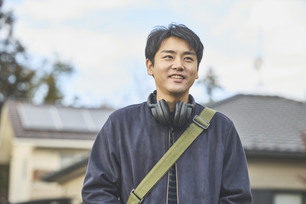 茂木優輝を演じる泉澤祐希。ヘッドホンを首にかけ、住宅街で空を見上げる。