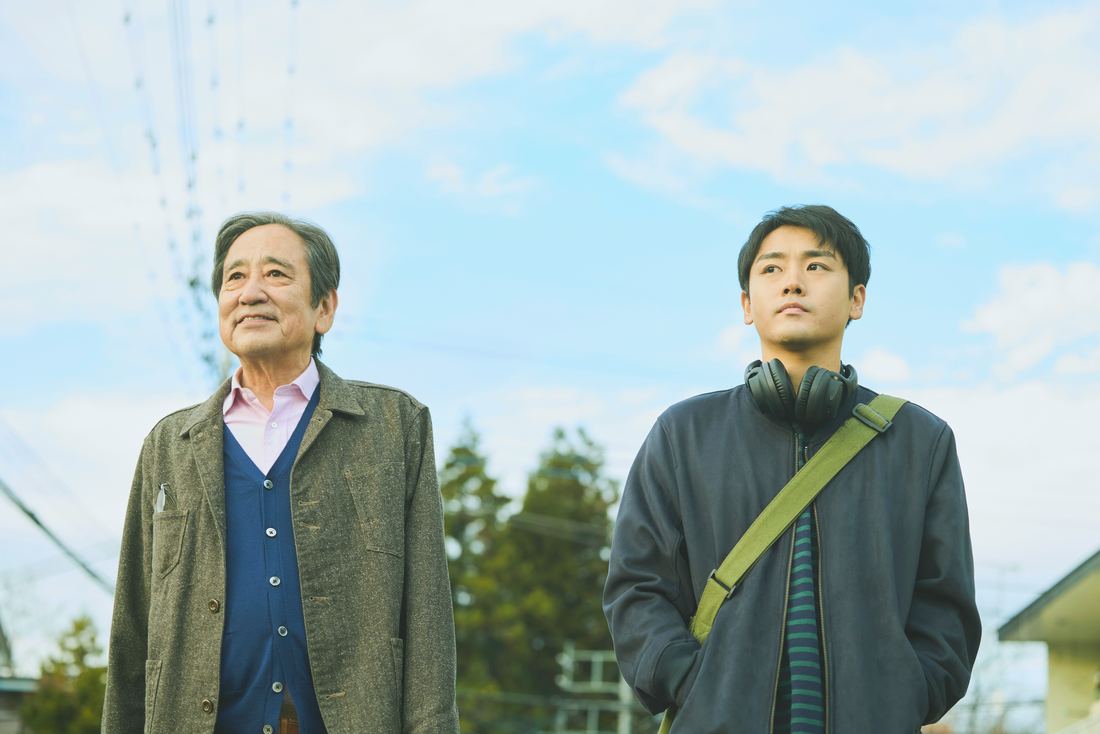 場面写真：晴れた住宅街の道で、並んで前を見つめる豊と優輝。